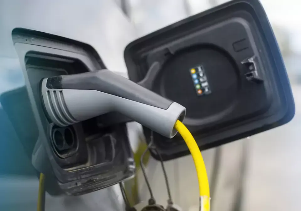 Ficha de carregamento com cabo amarelo ligada à porta de carga de um carro elétrico