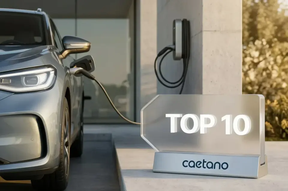 Carro cinzento a carregar num carregador de parede, junto a uma placa de vidro com o texto "Top 10 Caetano"