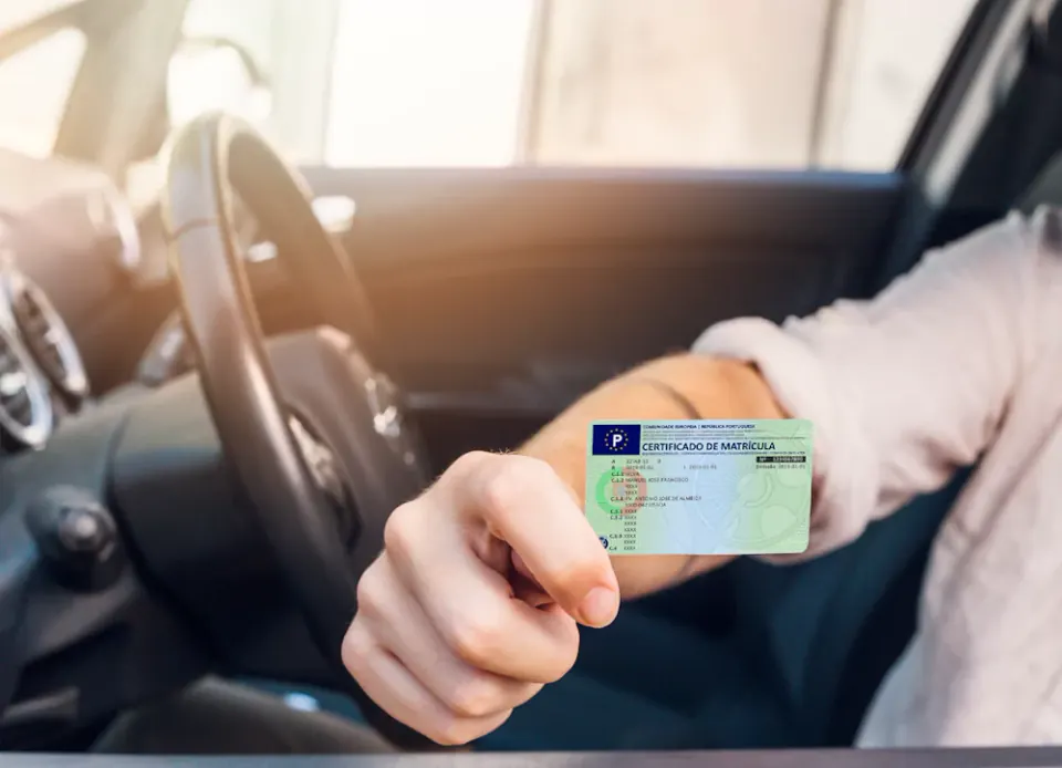 Pessoa dentro do carro a mostrar o DUA (Documento Único Automóvel)